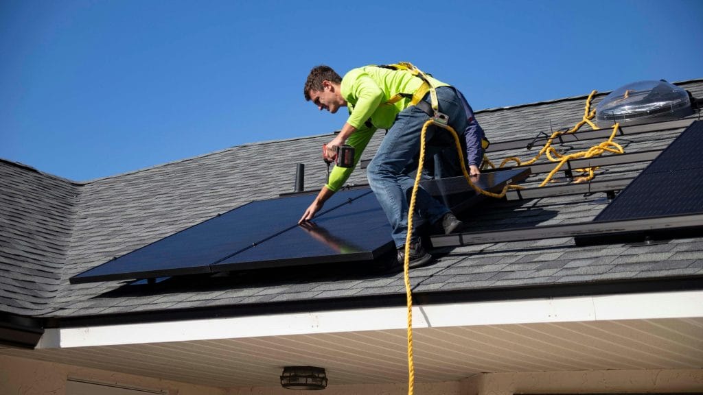 persona en un tejado instalando aerotermia con placas solares