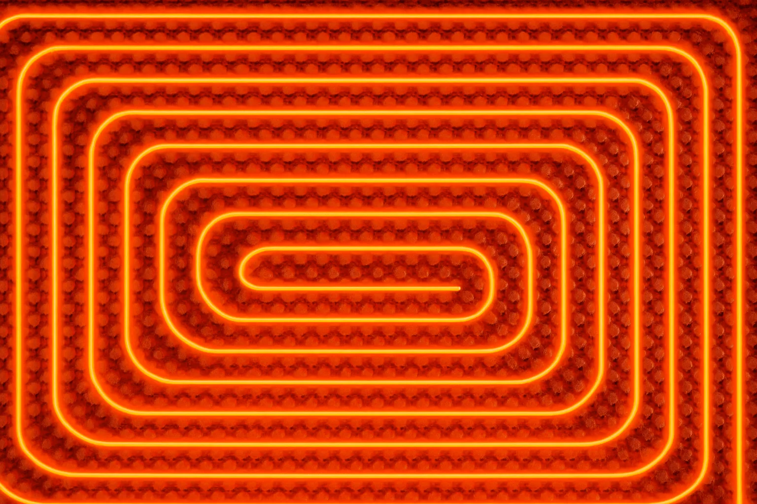 Circuito de suelo radiante en serpentín sobre panel aislante, con los tubos iluminados para mostrar cómo reparte el calor